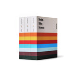 A boxed set of three books standing upright on a white background. The spines are white with multicolor stripes, and the front cover reads 'feels like home' in black text.