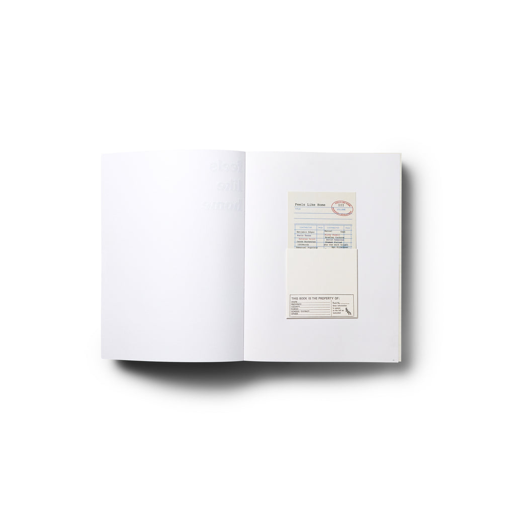 Open book showing a mostly white interior spread with a small card inserted on the right page