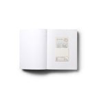 Open book showing a mostly white interior spread with a small card inserted on the right page